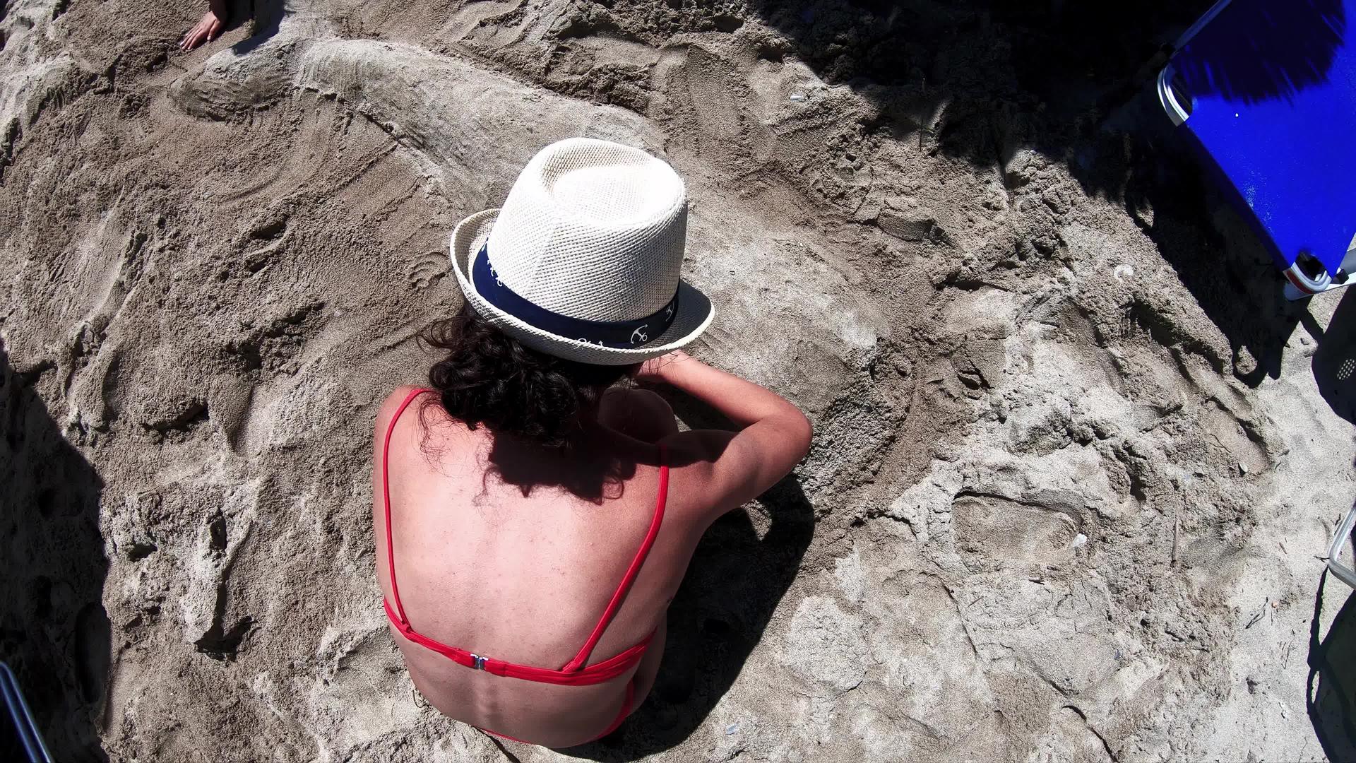创意女孩戴着比基尼比基尼草帽在海滩上用沙子做成形状视频的预览图