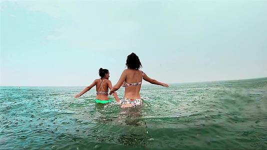 下雨时快乐的姐妹们在浅海里玩得很开心视频的预览图