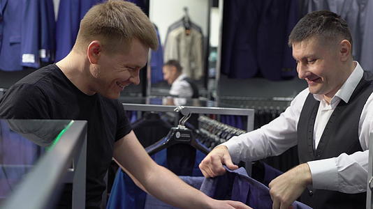 购物和时尚概念青年男子在商场选择和试穿夹克视频的预览图
