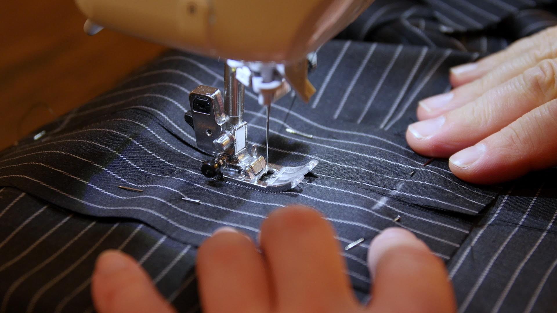 女裁缝在缝纫机上缝制黑色条纹布制成的衣服内置硬件视频的预览图