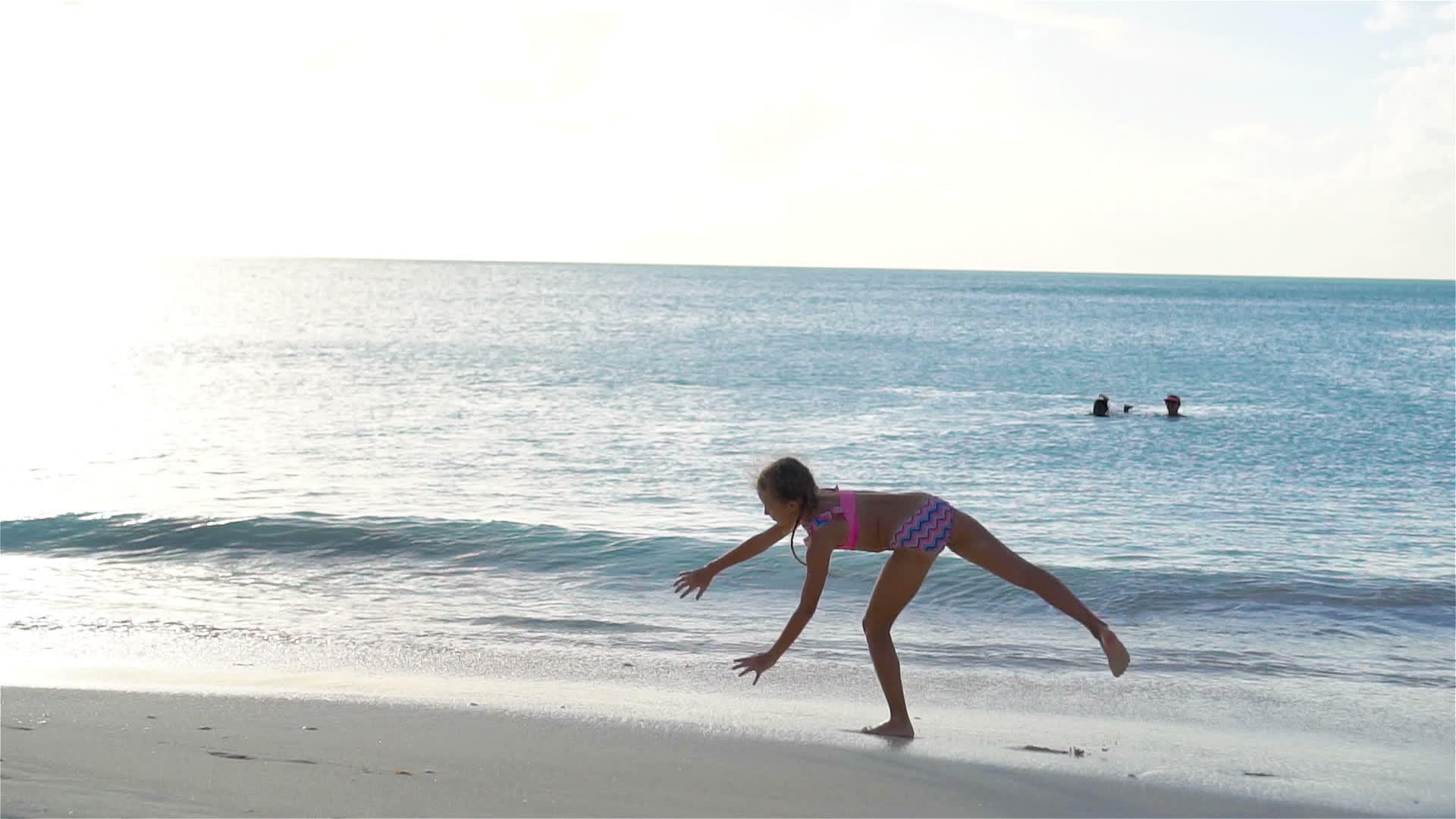 活跃的小女孩在白色沙滩上锻炼在海岸上锻炼体操慢慢动作视频的预览图