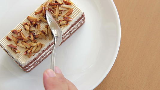 用手在白盘盘子上切焦糖咖啡蛋糕甜甜点视频的预览图