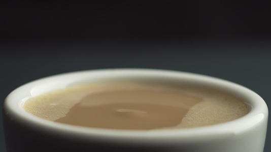 咖啡从咖啡机滴入白色陶瓷杯的慢动作微距镜头黑色背景视频的预览图