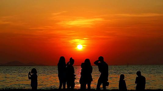 海滩上有六个人拍海边日落的照片视频的预览图
