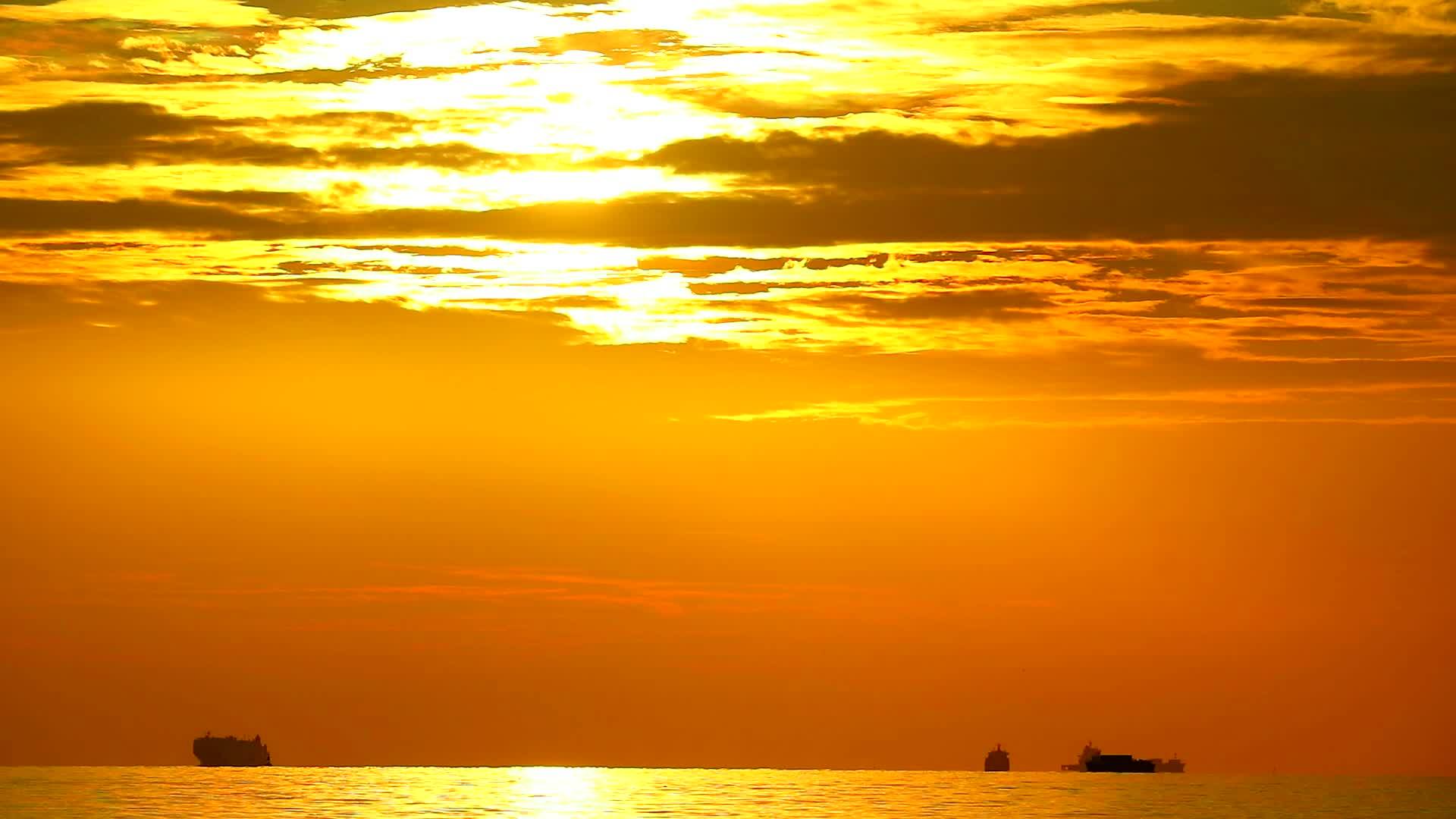 海边深橙色云雾移动和货船日落视频的预览图