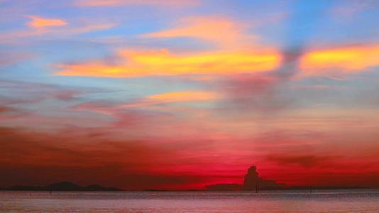 黑暗的海面上模糊的日落、红色和蓝色的天空和黄橙色的云彩视频的预览图