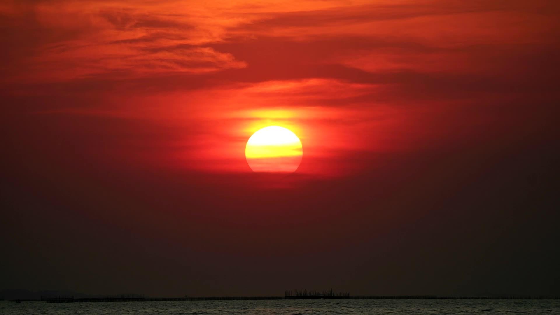 太阳在黑暗的天空和红色的橙色云彩中照耀着大海视频的预览图
