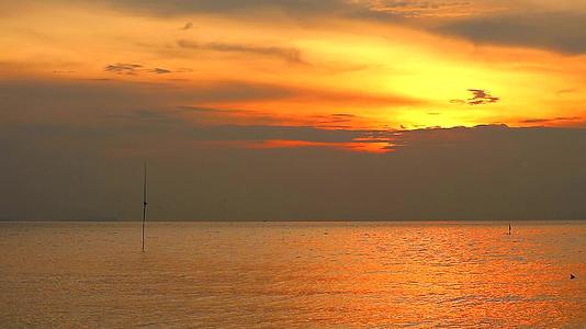 日落的橙色天空和深黄色的云朵在海面上飘动视频的预览图