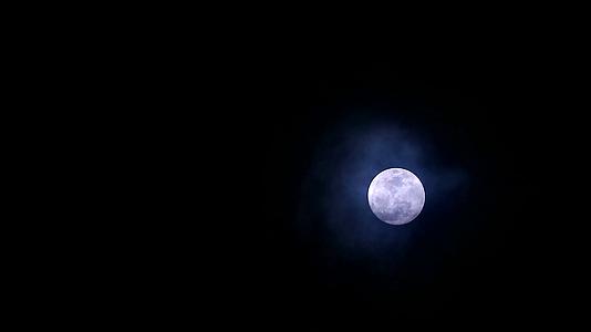 寒冷的月亮在夜空中柔和而黑暗的乌云中移动视频的预览图