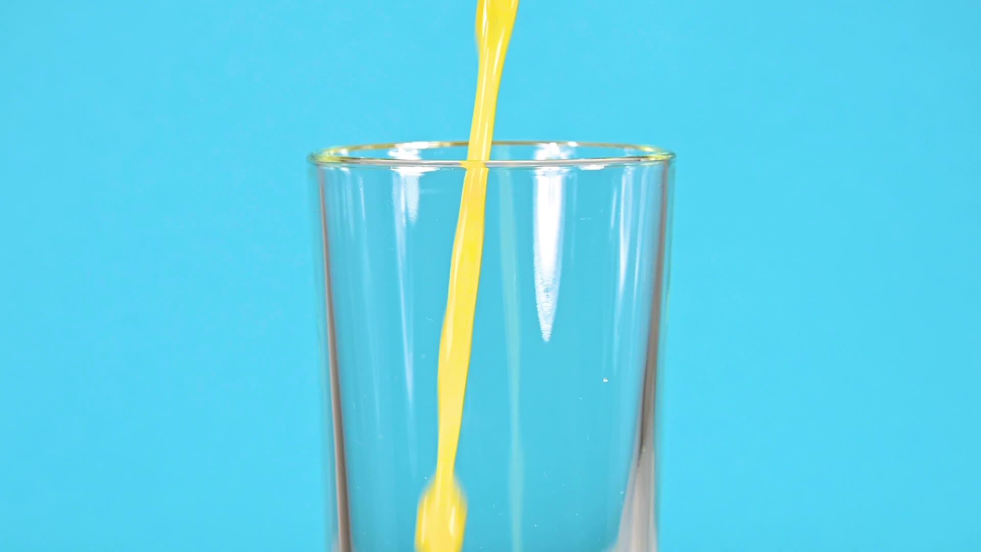 把橙汁倒在玻璃杯里的蓝色杯子上视频的预览图