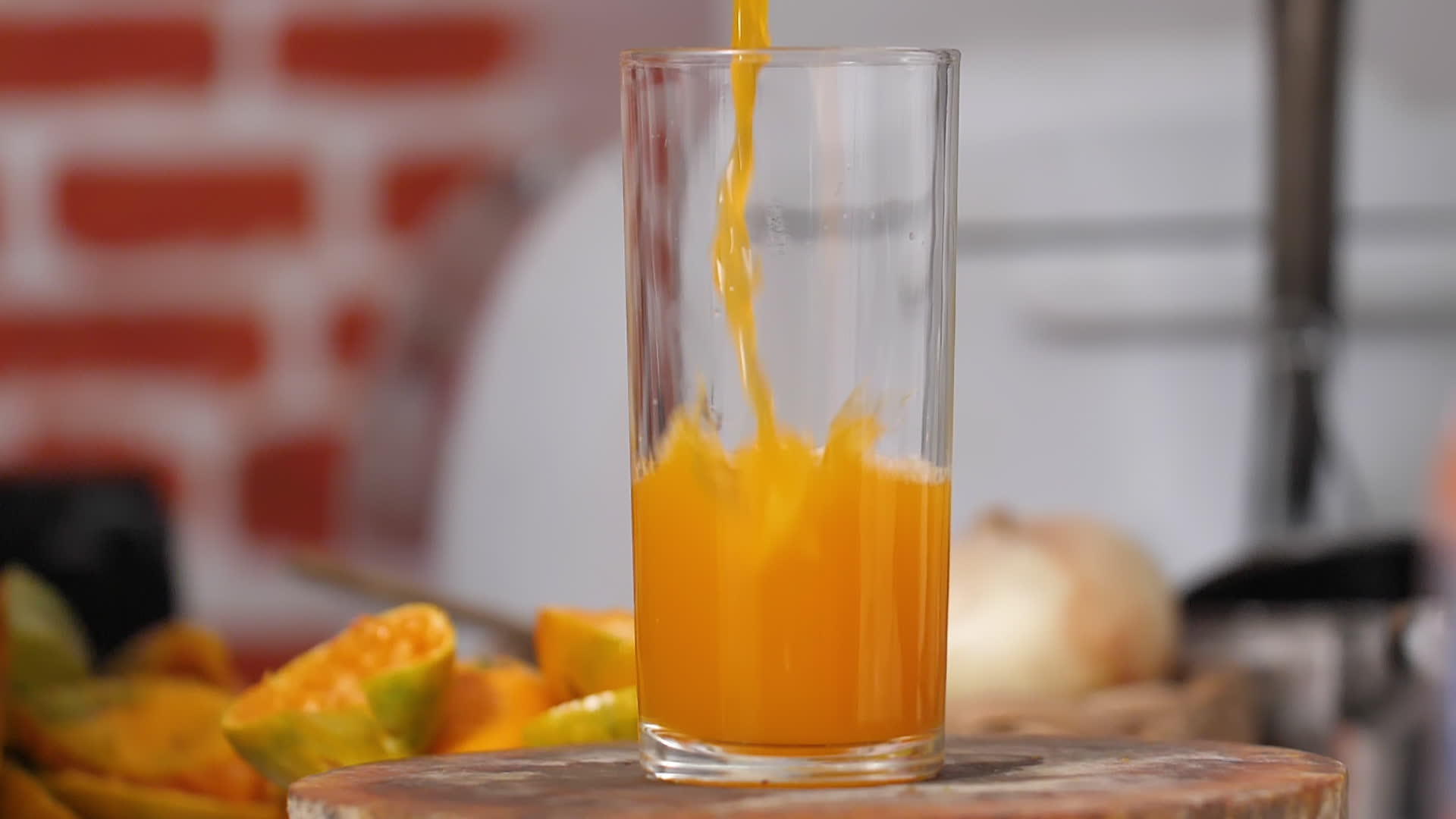 把橙汁倒在厨房的剪板上在一个清澈的玻璃杯里视频的预览图