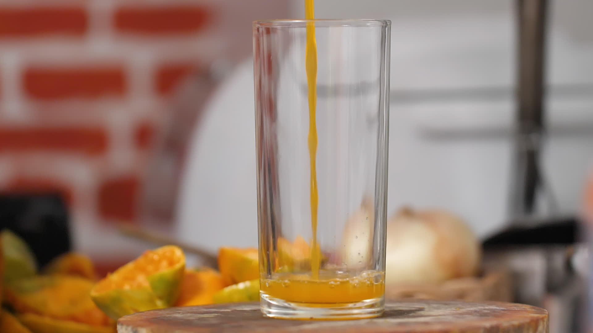 把橙汁倒在厨房的剪板上一个清晰的玻璃杯视频的预览图