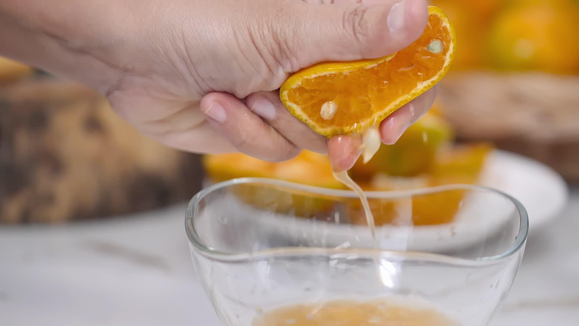 将近挤压的橙汁伸入厨房桌子上的透明玻璃杯中视频的预览图