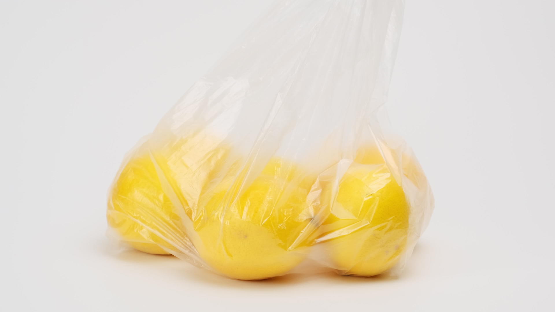 成熟的黄柠檬在白色背景的透明塑料袋中拒绝塑料制品；视频的预览图