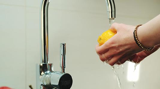 女人在水龙头下用手洗柠檬水视频的预览图