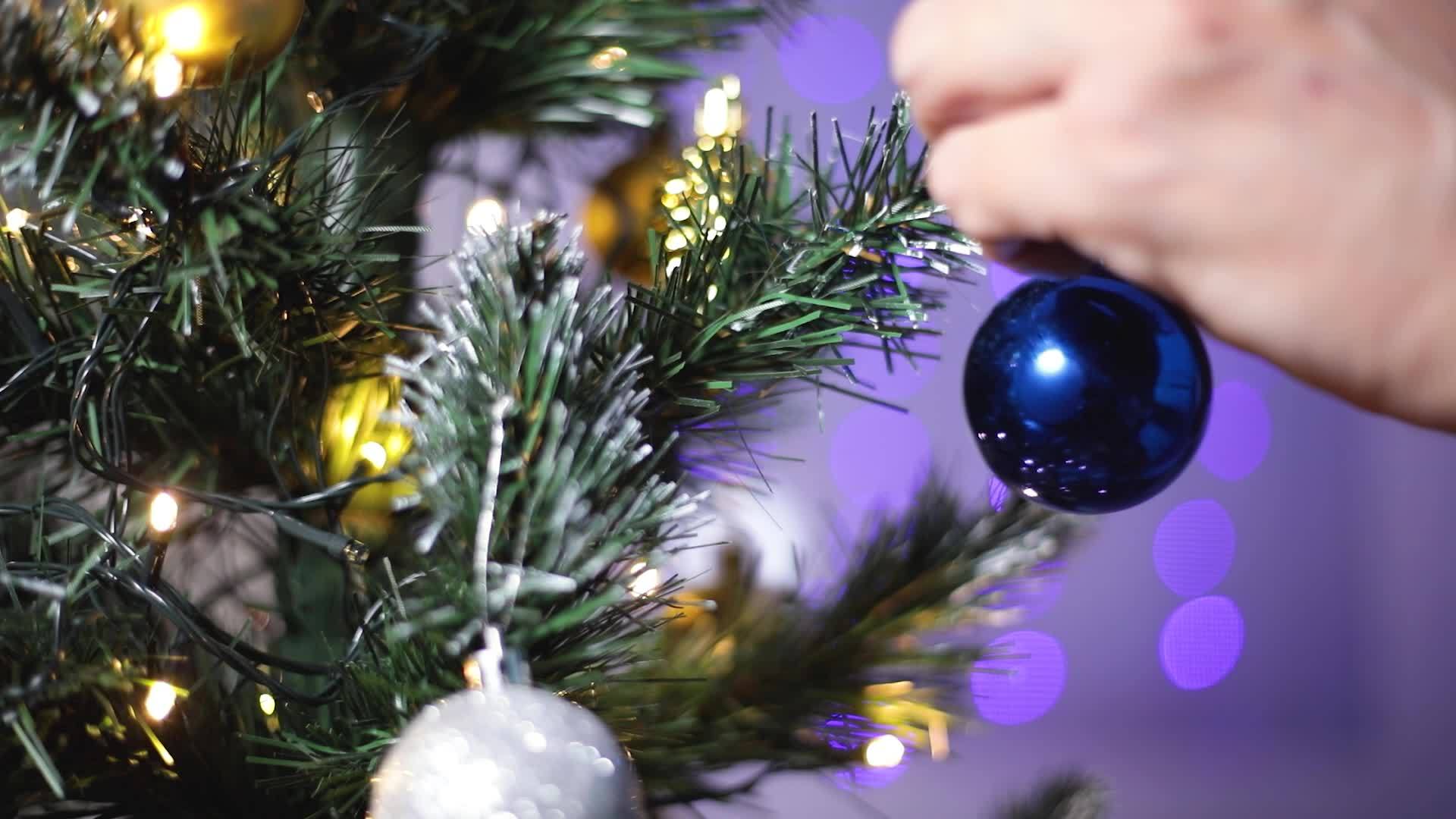 一个人的手把玩具球挂在圣诞树上视频的预览图