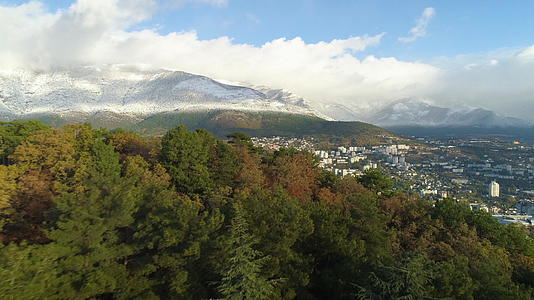 飞向城市的雪山在空中观望在背景中建立明亮的山峰视频的预览图