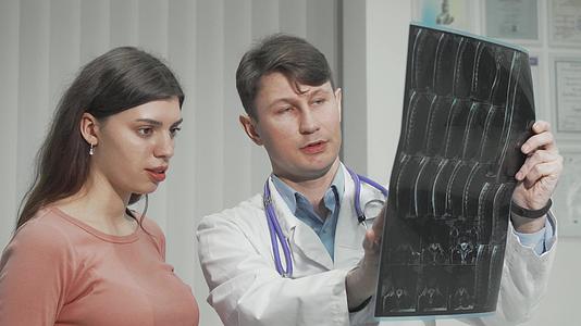 男医生向女病人解释MRI调查结果视频的预览图