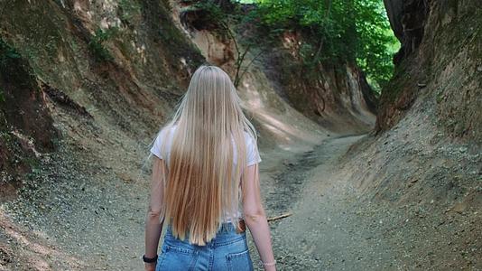 美丽的金发美女在自然峡谷中漫步视频的预览图