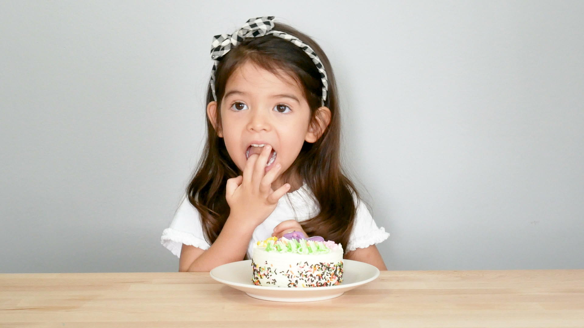 可爱的小女孩藏着用手指吃着蛋糕脸上带着害羞的脸孩子们混合着种族视频的预览图