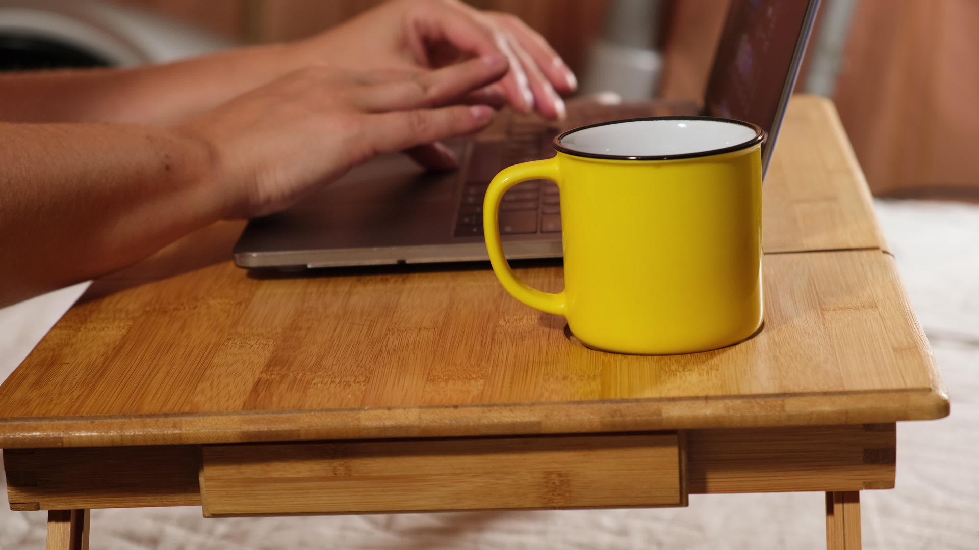 两只女手和一台笔记本电脑放在木床边的桌子上视频的预览图