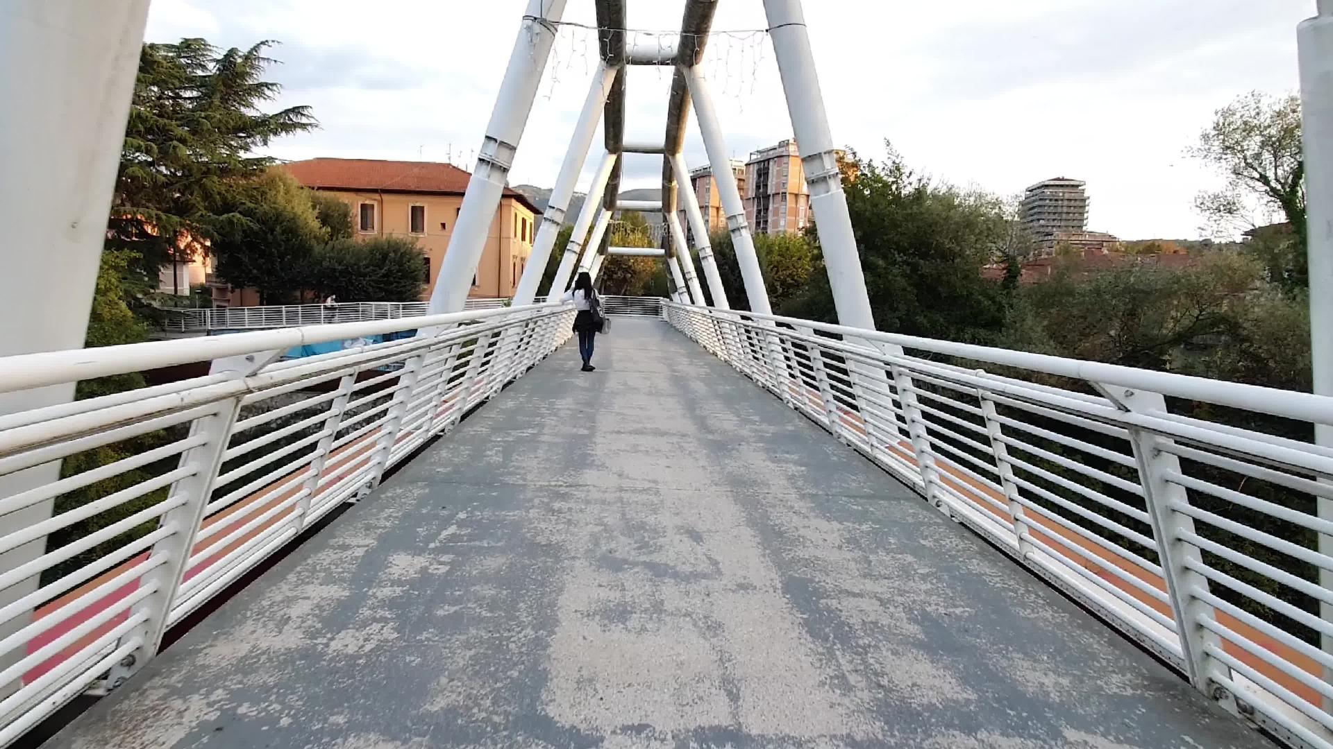 走在横跨河流的金属桥上视频的预览图