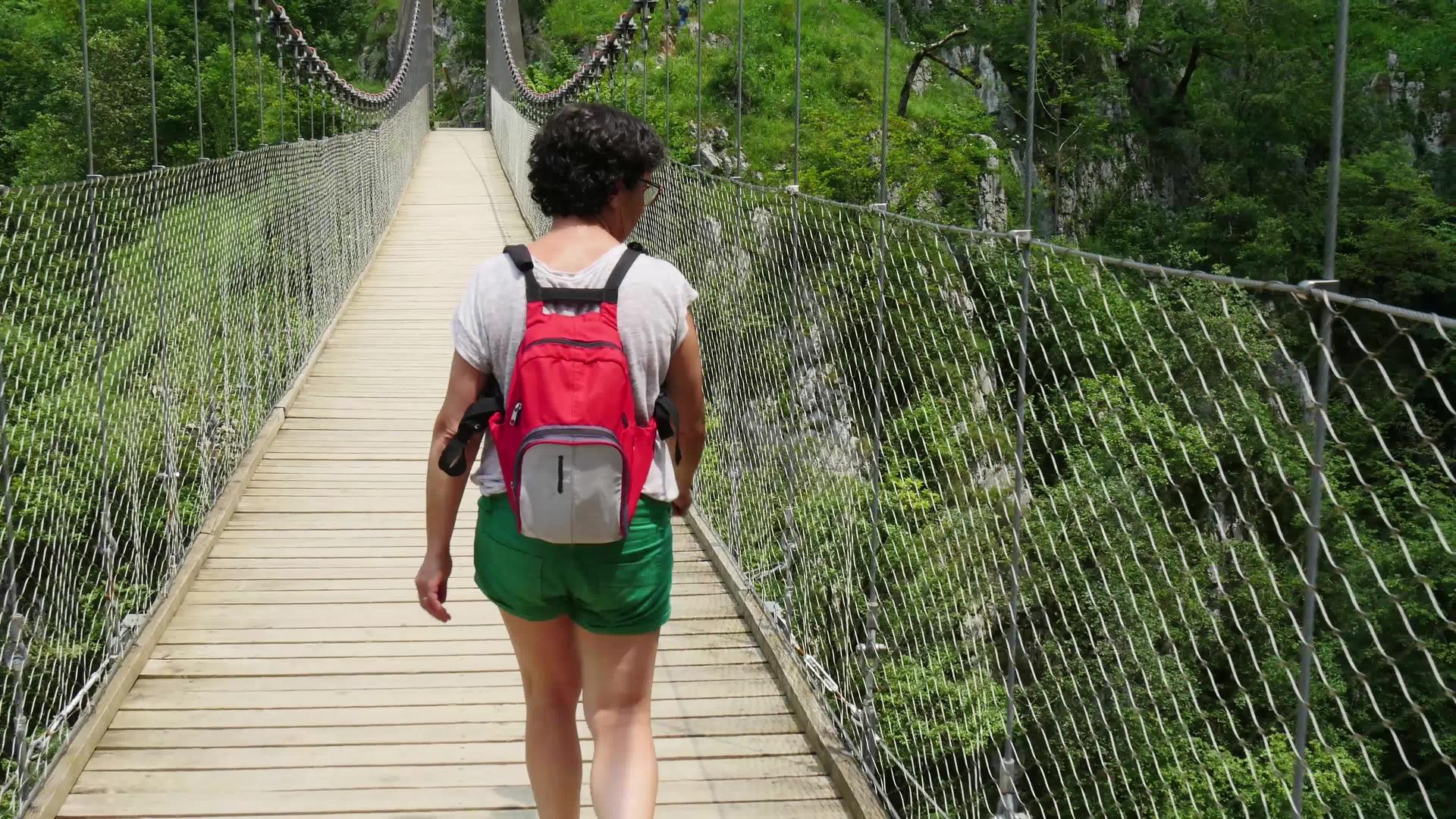 女性徒步旅行者在比利牛斯的霍尔扎特吊桥上行走视频的预览图
