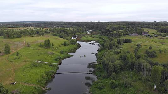 在偏远村庄的偏远河流上暂停的桥接近空中视频的预览图