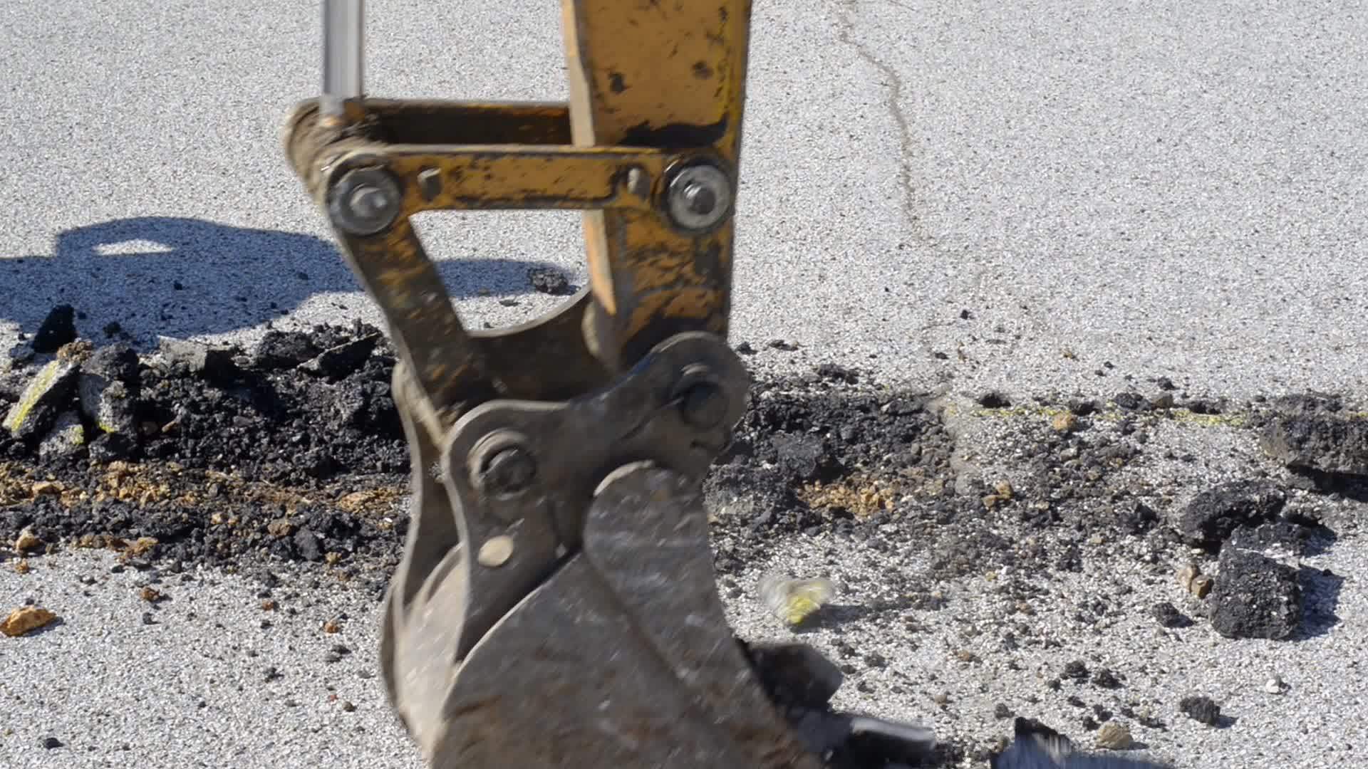 装有窄桶的小型挖掘机清除铺路沥青视频的预览图