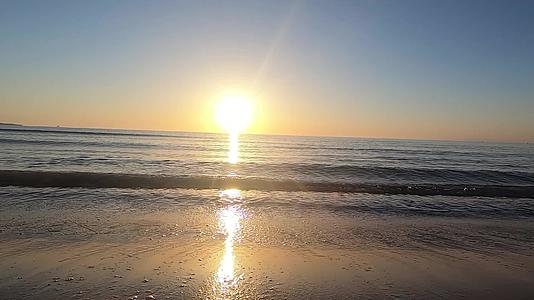 靠近地面的岸边移动着碎片黎明时在后光沙中落下的小波浪视频的预览图