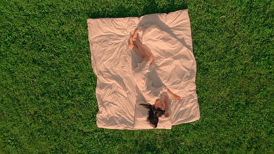 无人驾驶无人机躺在白床草地上的绿草雌鸟上方视频的预览图