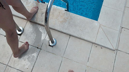 快乐的年轻女子在梯子上穿着黑色泳衣进入无限泳池——夏天视频的预览图