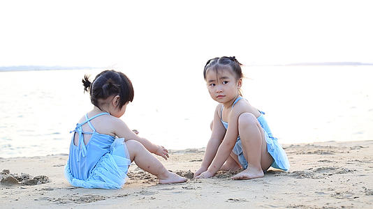 夏日夕阳下儿童在海边沙滩上玩沙子视频的预览图