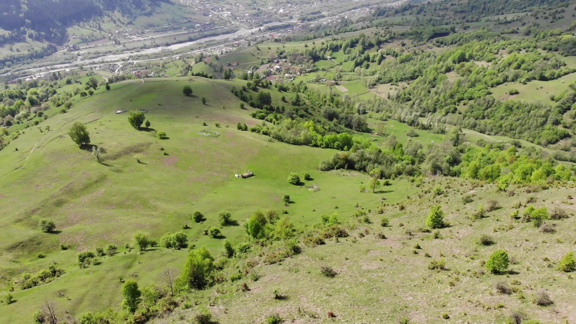 无人机飞越绿谷和村庄鸟瞰后面的山丘和村庄视频的预览图