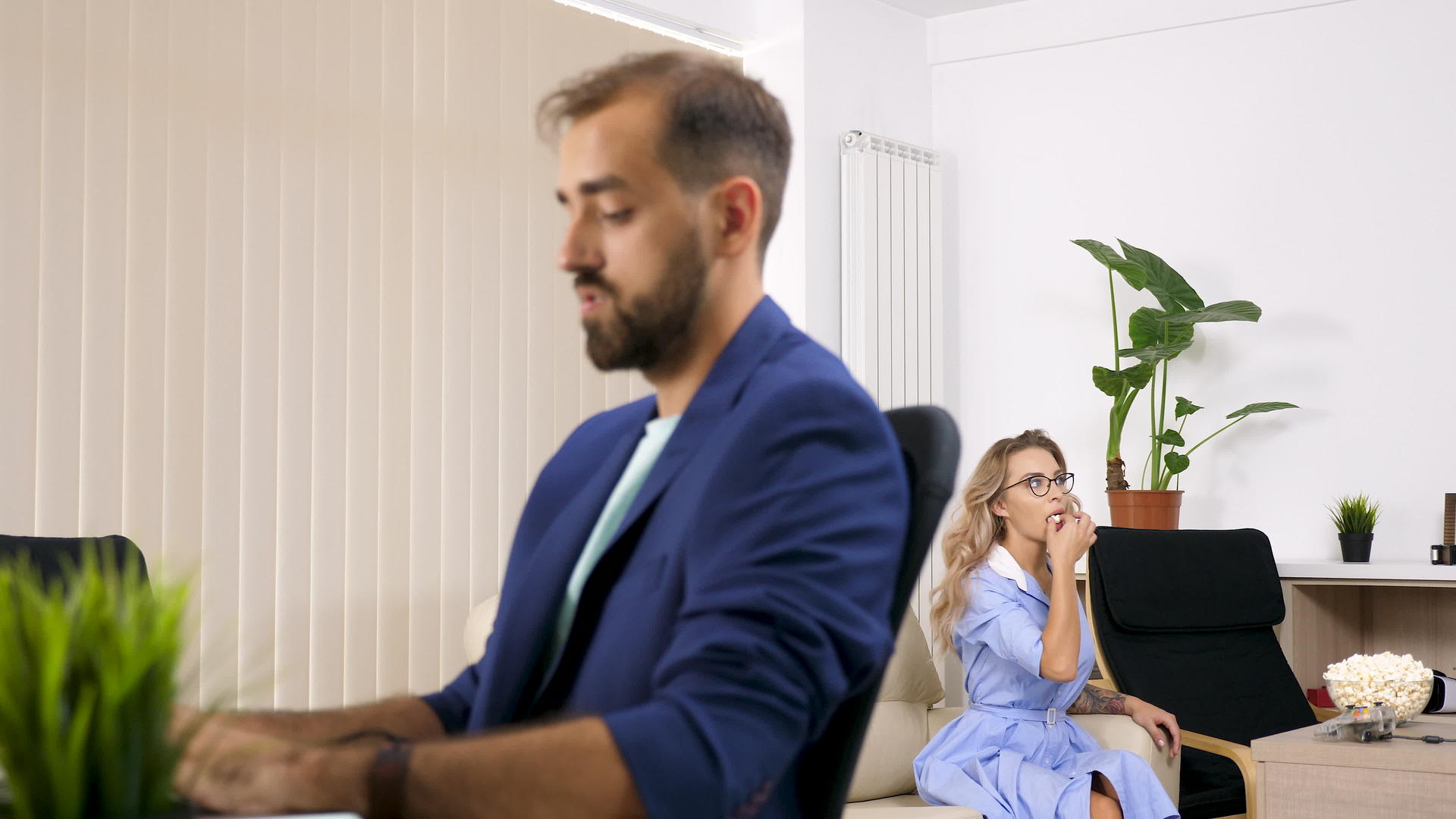 女人看电视吃爆米花男朋友在电脑上工作视频的预览图