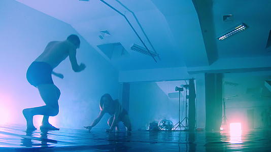 一对性感的情侣在蓝色烟雾背景的剪影背后跳舞视频的预览图