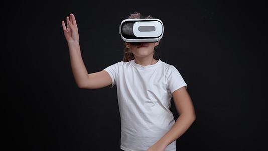 快乐的10岁女孩穿着黑色背景的30岁女孩D挥舞虚拟现实眼镜视频的预览图