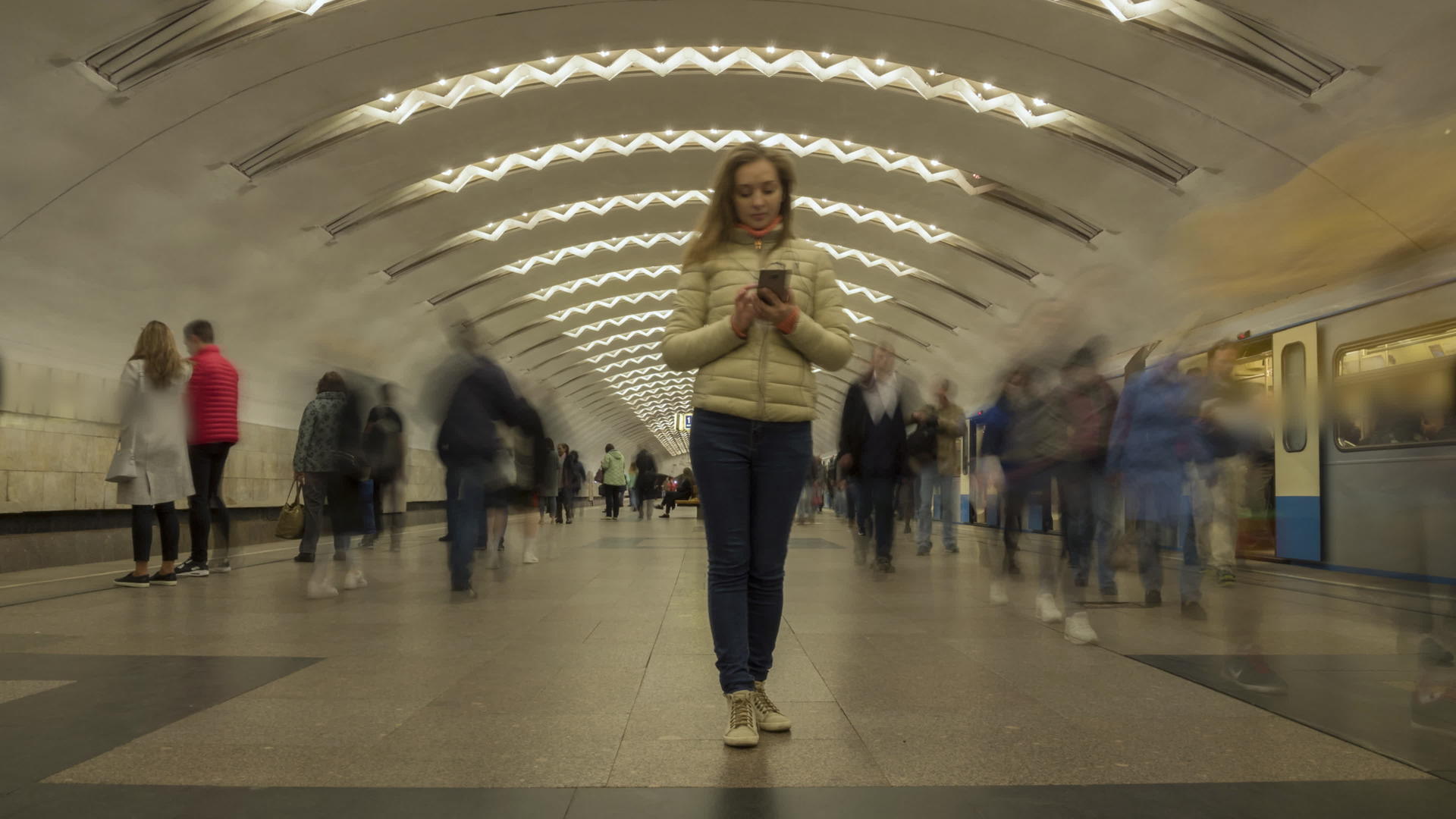 妇女站在地下地铁站使用手机时间间隔人群聚集视频的预览图