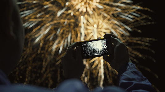在夜空中拍摄烟花的男人的休眠是为了纪念这个节日视频的预览图