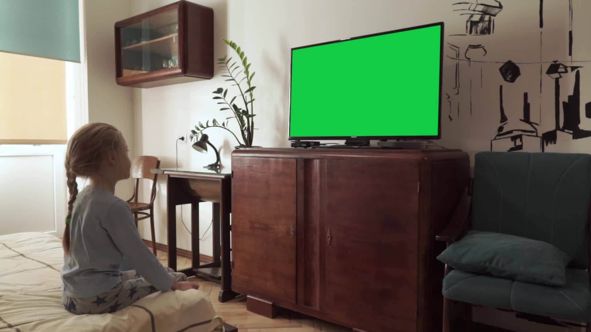 白人金发女孩在卧室的床边看着有一个绿色的屏幕色度键视频的预览图