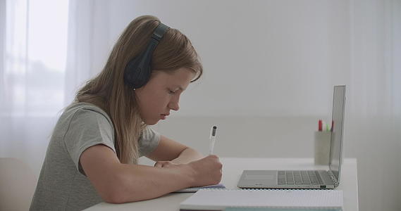 学校的女生正在做作业坐在房间的桌子上用笔记本电脑视频的预览图