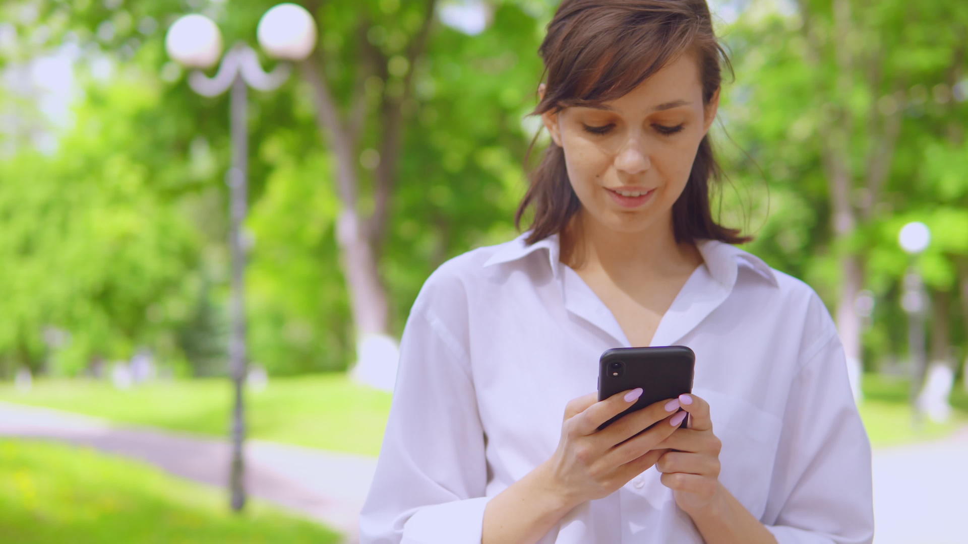 千百年女孩在公园里用手机在线聊天视频的预览图