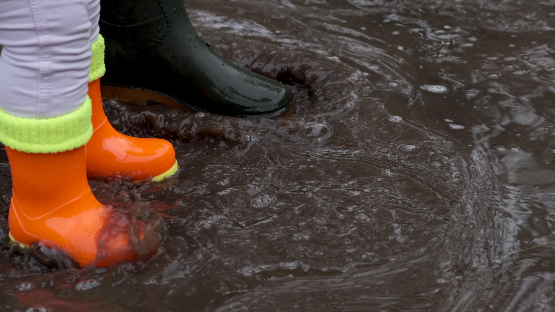 孩子和成人橡胶靴穿过水坑慢慢地笑视频的预览图