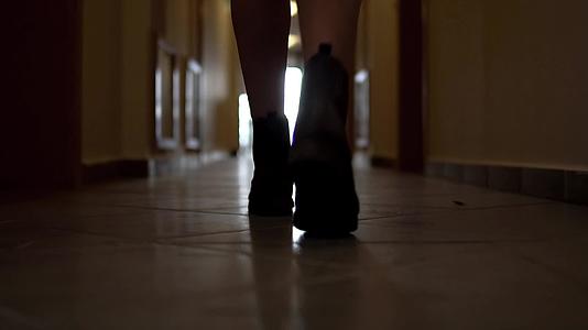 追逐穿着难以辨认的靴子的女人的脚步声沿着黑暗走廊行走视频的预览图
