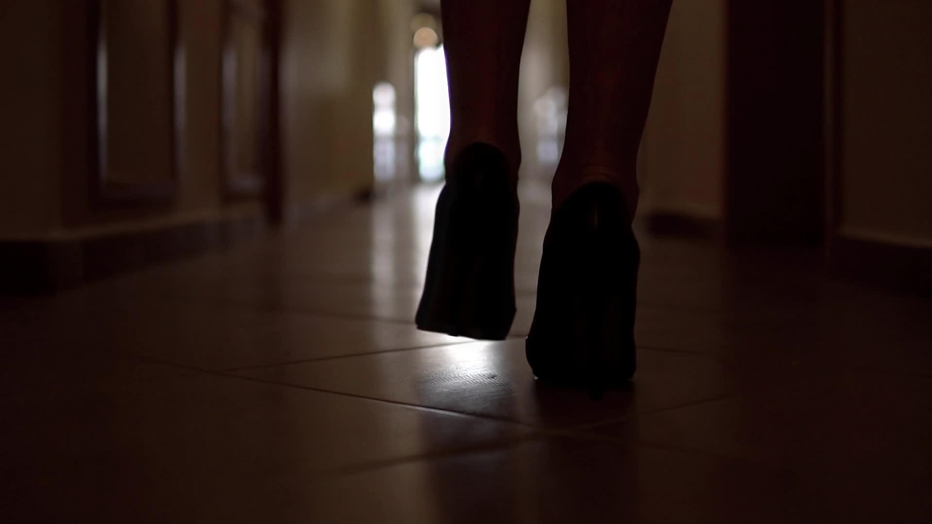 追着穿着高山鞋的无法辨认的女人的脚步沿着黑暗走廊走着视频的预览图