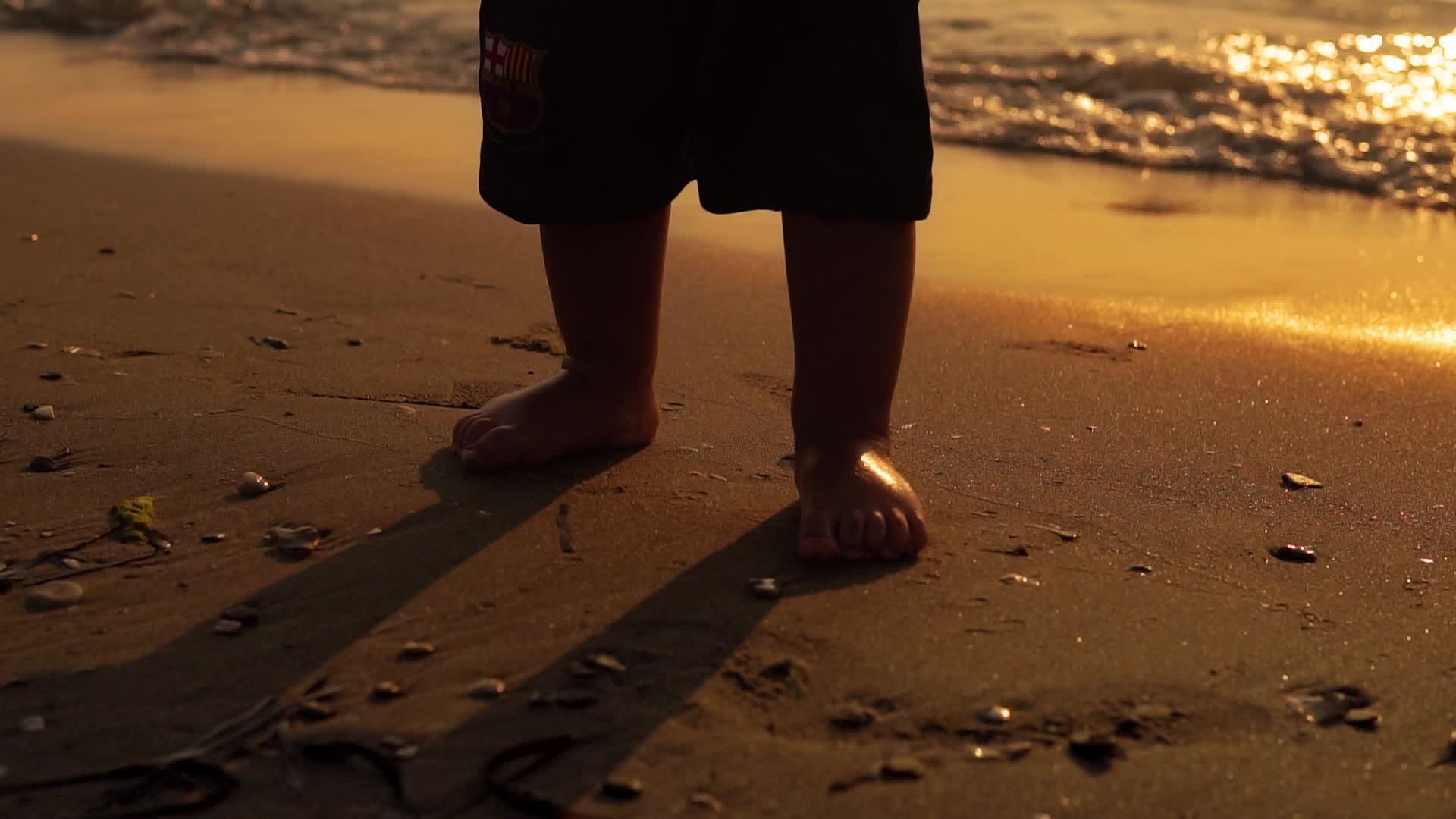 婴儿和婴儿在海上日落沙上迈出了第一步视频的预览图