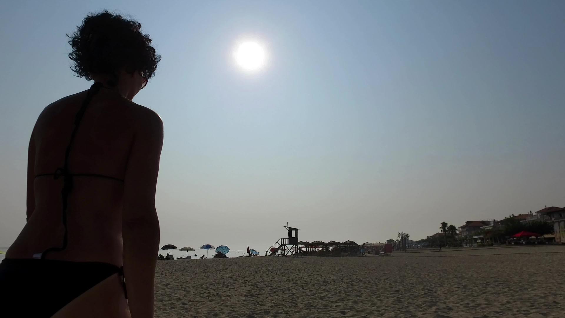 女人在空荡荡的沙滩上向太阳的光束走去从天空的一侧往下看四公里视频的预览图