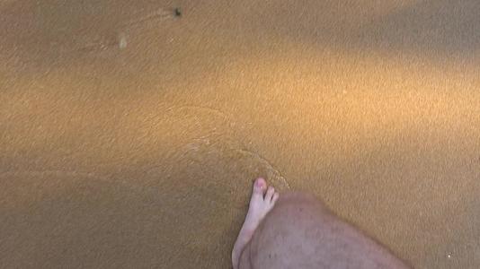 男人脚的顶部景色在海滩上行走视频的预览图