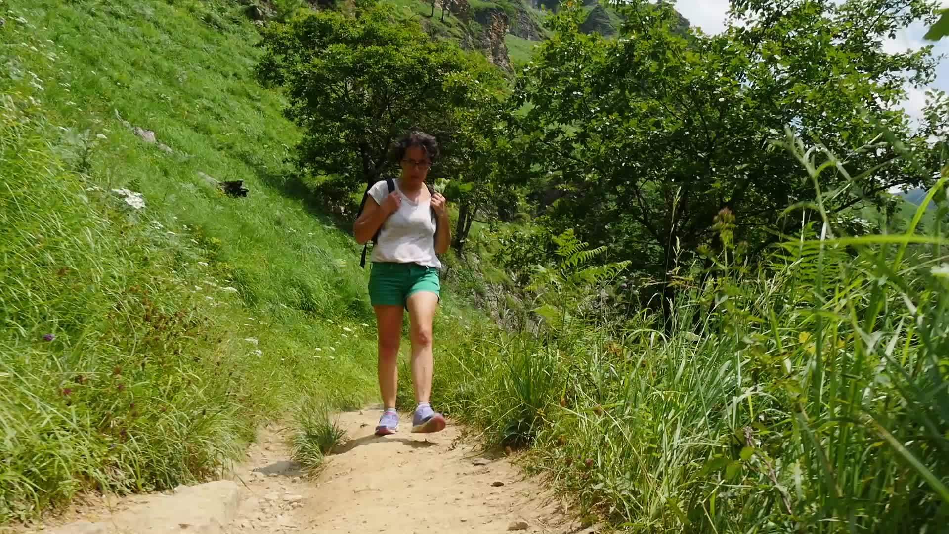 女性徒步旅行女性徒步旅行者在山路上行走视频的预览图
