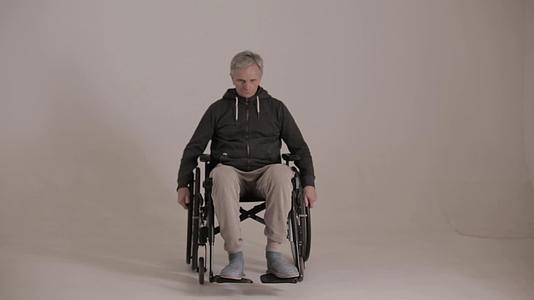 一个灰色头发的男人坐在轮椅上脸是白色背景的邪恶表情视频的预览图